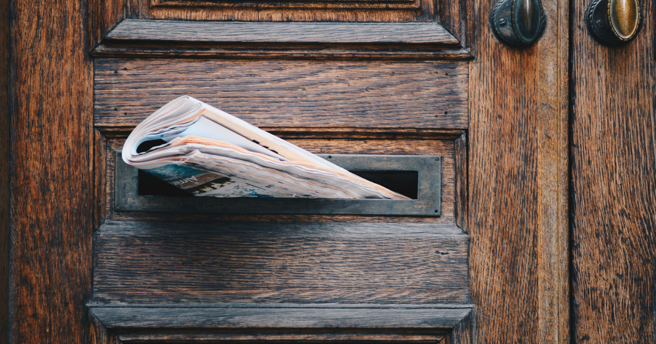 a newspaper sticking out of a mail slot of a door