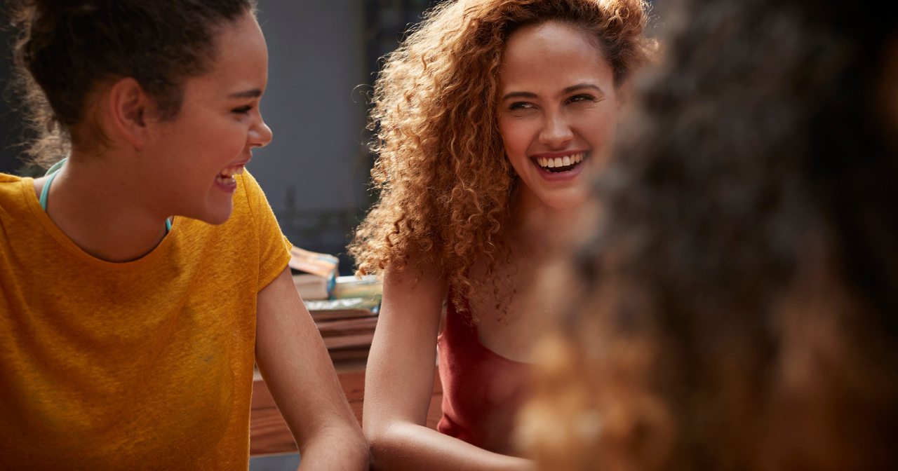three millennial women laugh and talk 