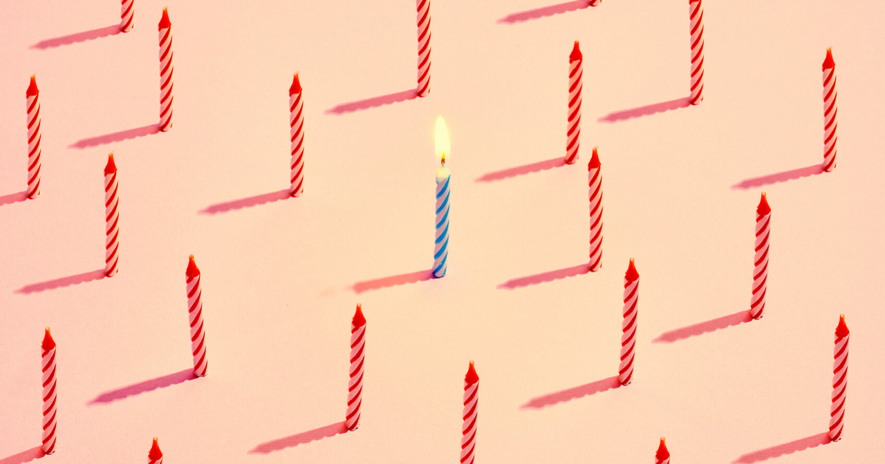 A sea of red, unlit birthday candles and one blue, lit candle in the middle. 