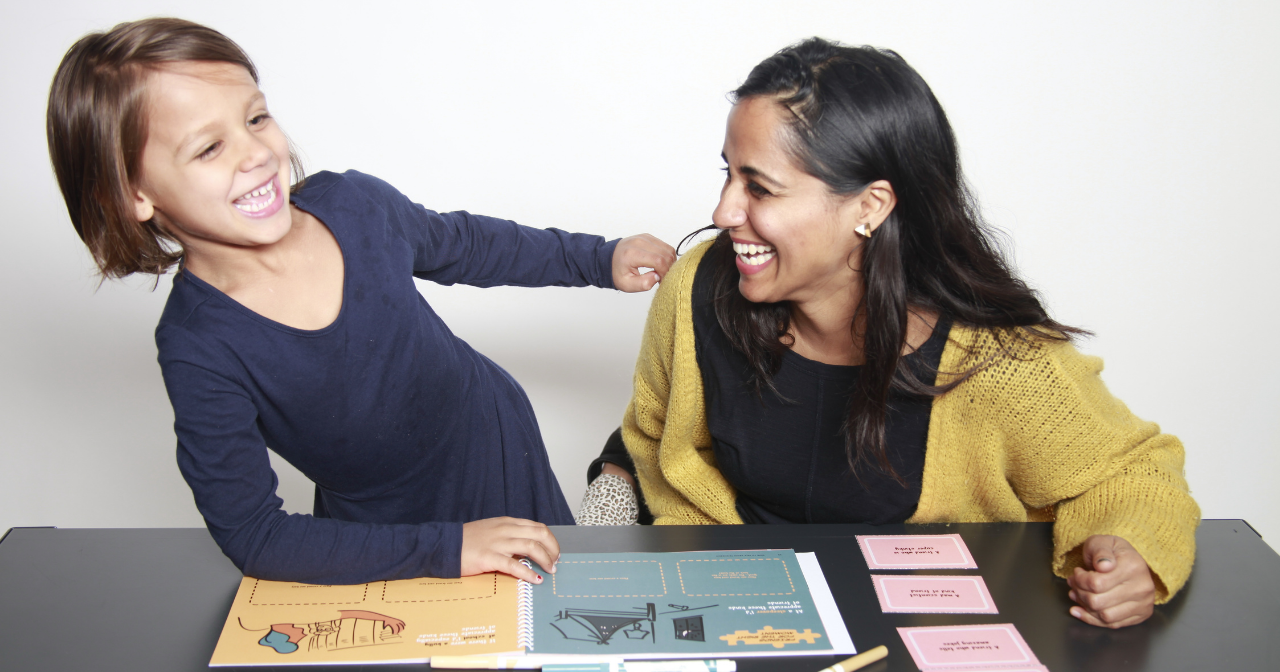 A mother and daughter laugh together while going through a Bloom playbook. 