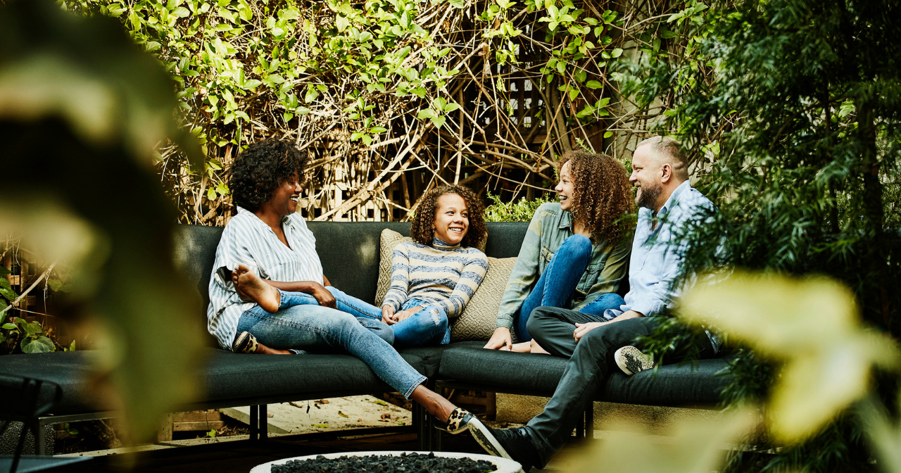 A family of four sits outside and talks and laughs together. 