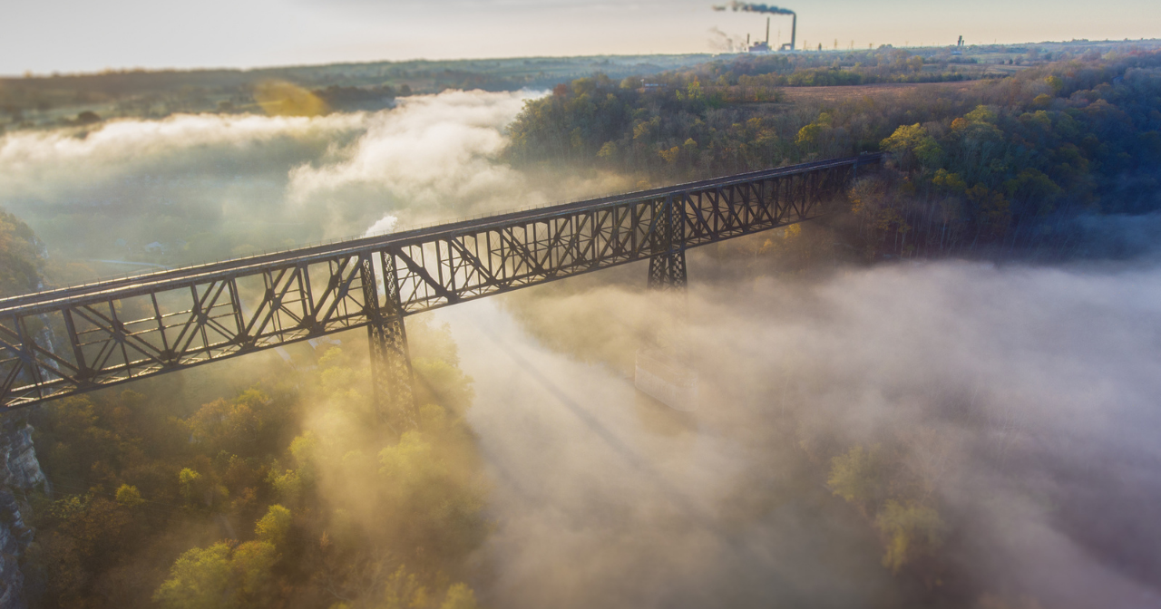 A photo of a bridge in Appalachian Kentucky surrounded by fog with sun beams peaking through. 