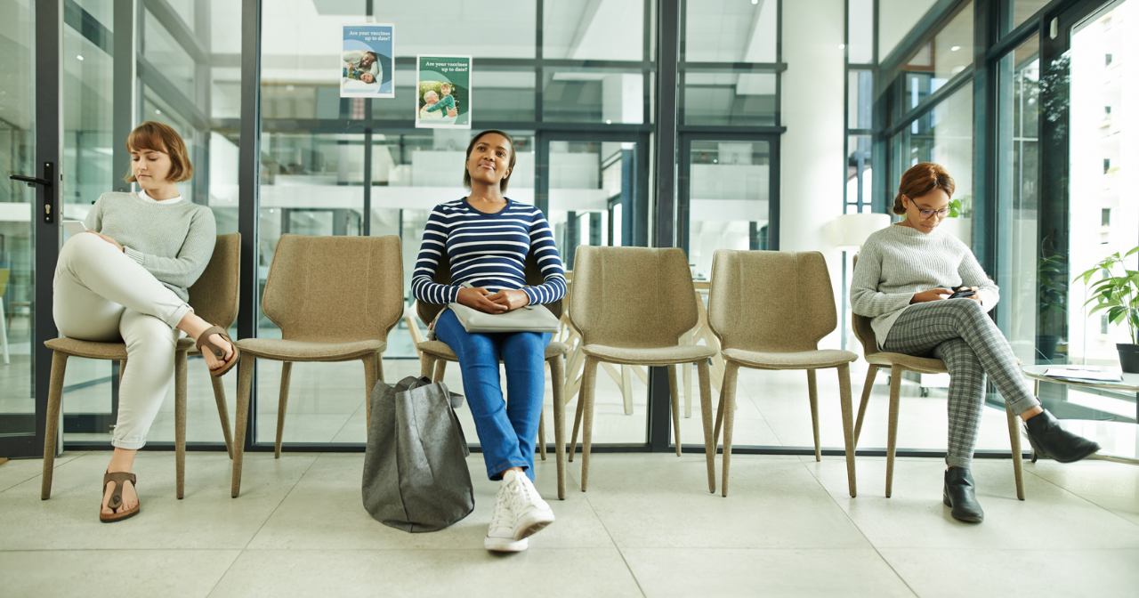 Three students sit in a waiting room at their college campus' health center. 