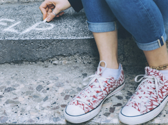 a woman drawing the word HELP in chalk on the sidewalk