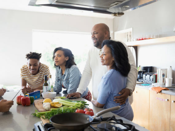 A family stands around a kitchen island and talks