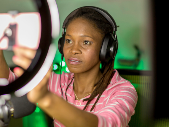 A Black women sets up a phone in a ring light. 