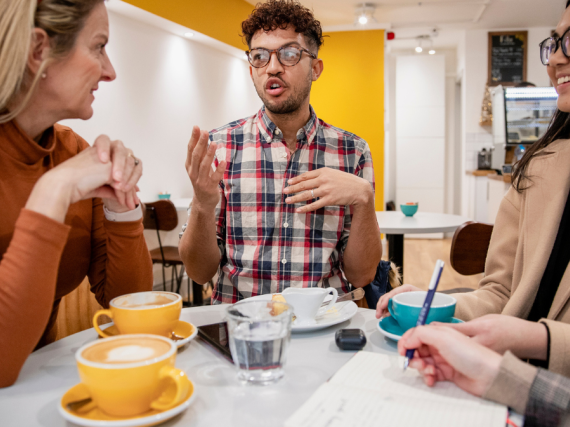 A small group of young people sit around a table and have an animated discussion. 