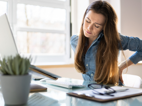 A woman sits at a desk and considers her screen while looking concerned. 