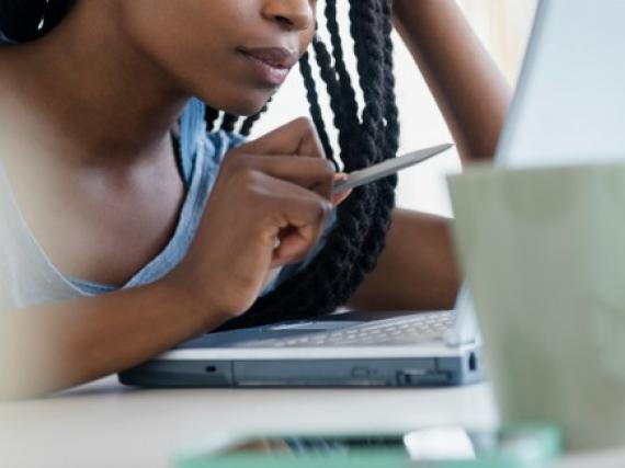 A woman sits at a computer looking concerned. 