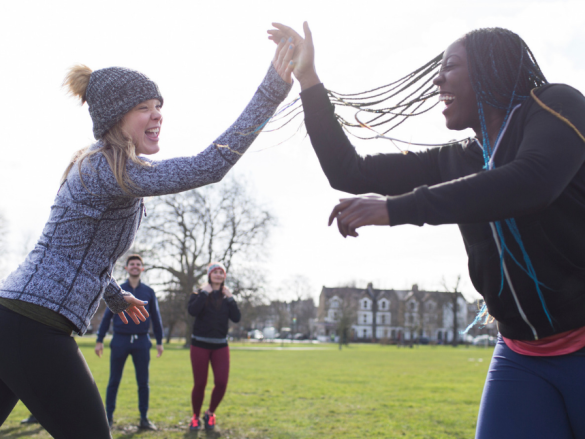 Two women high five in a field