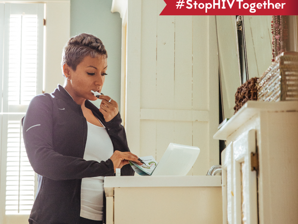 A woman stands in her bathroom and reads the instructions on an at-home HIV testing kit. 