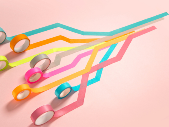 Eight different colors of tape are all rolled out and over one another. 