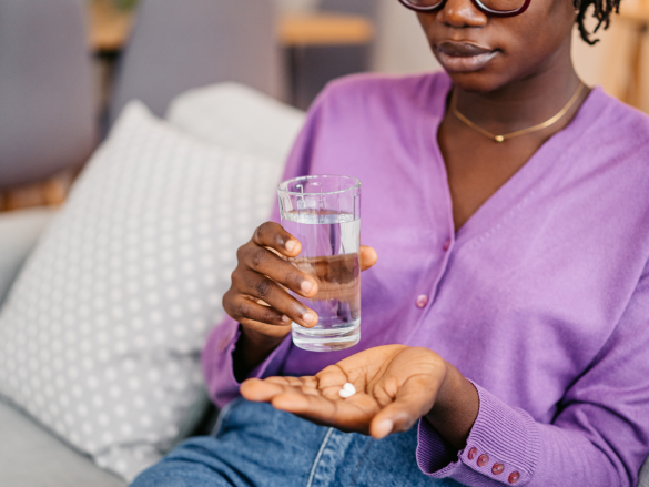 Woman taking a pill with water.